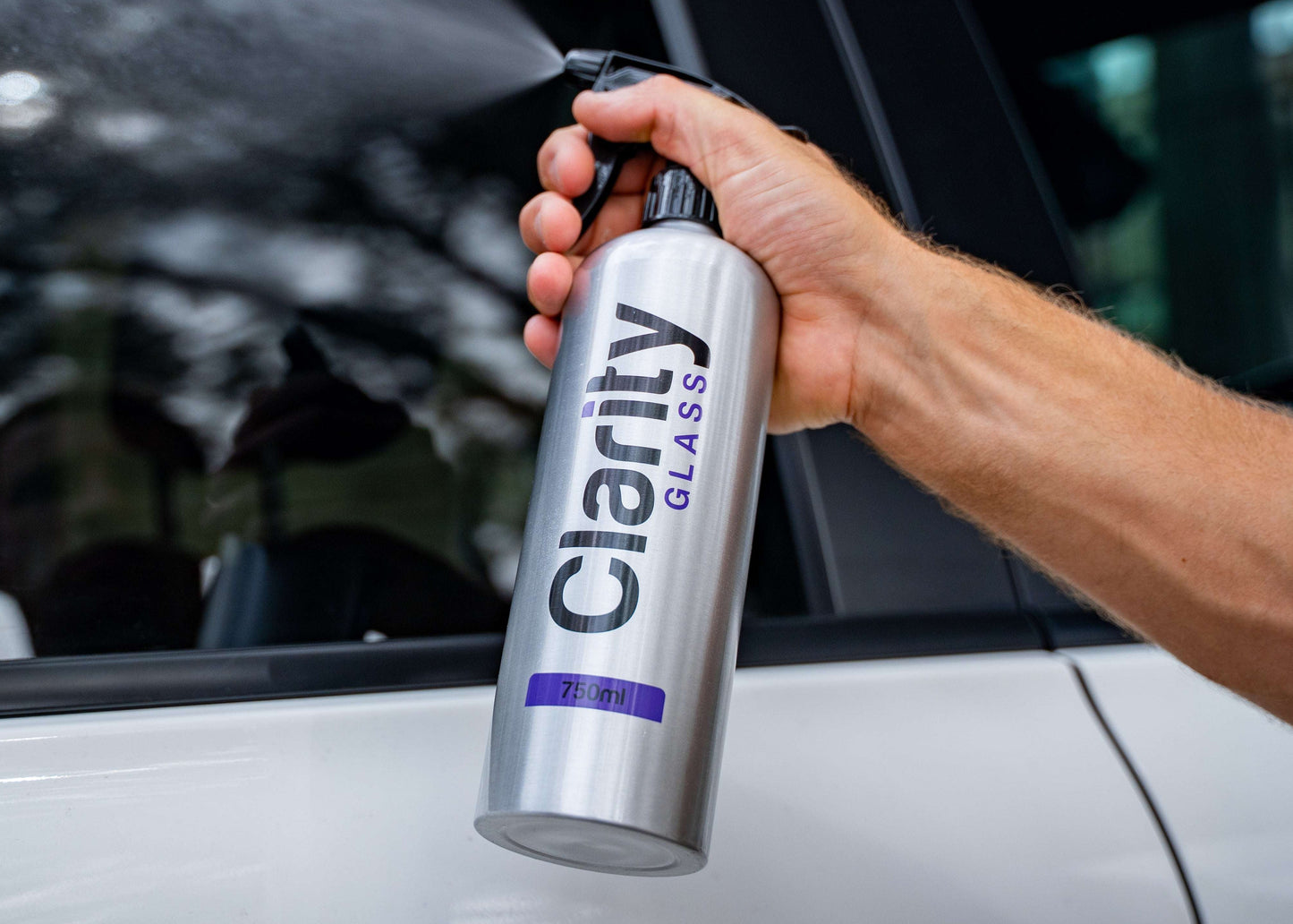 Person holding a Clarity Glass cleaner can in front of a car window