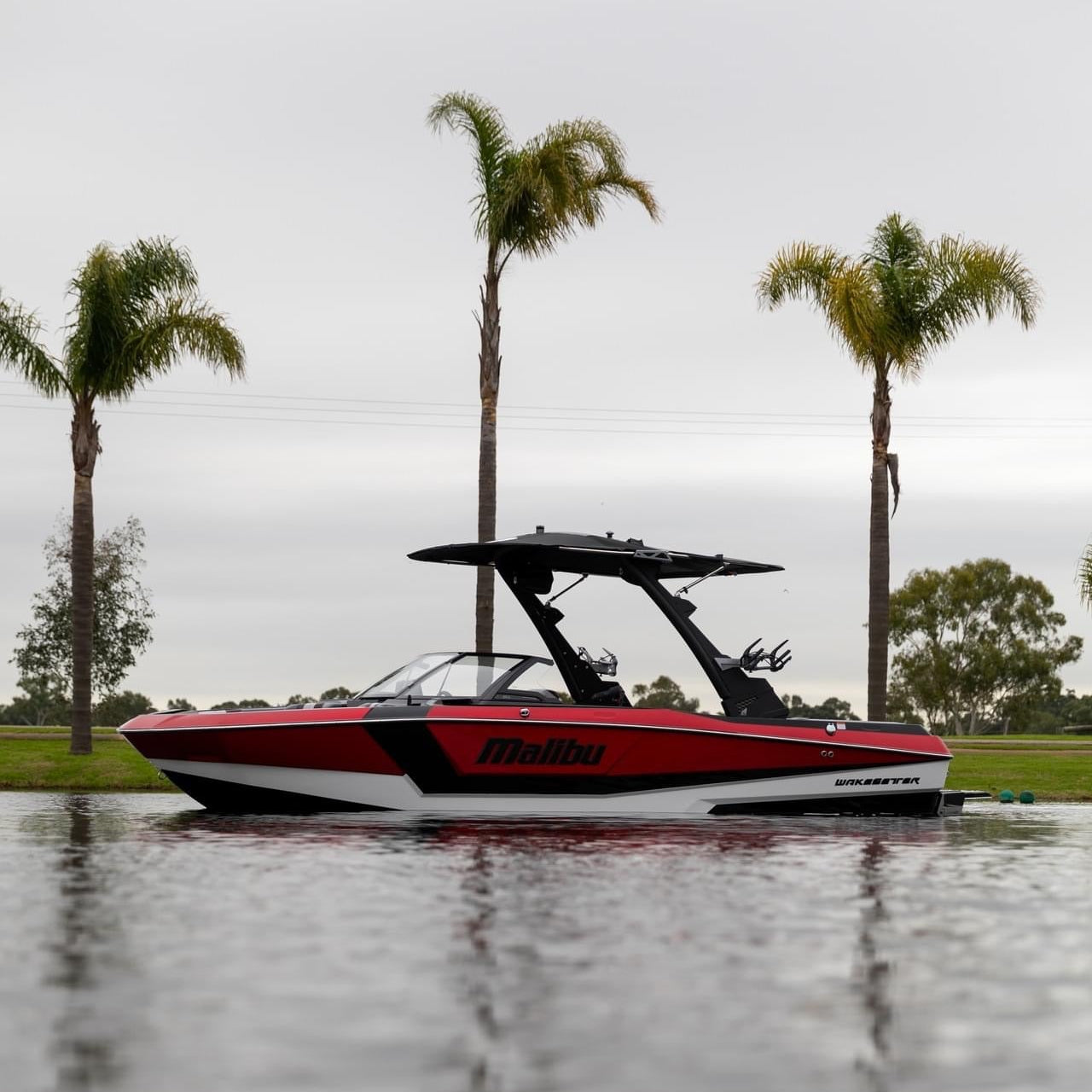 Red and black boat on water with palm trees in the background