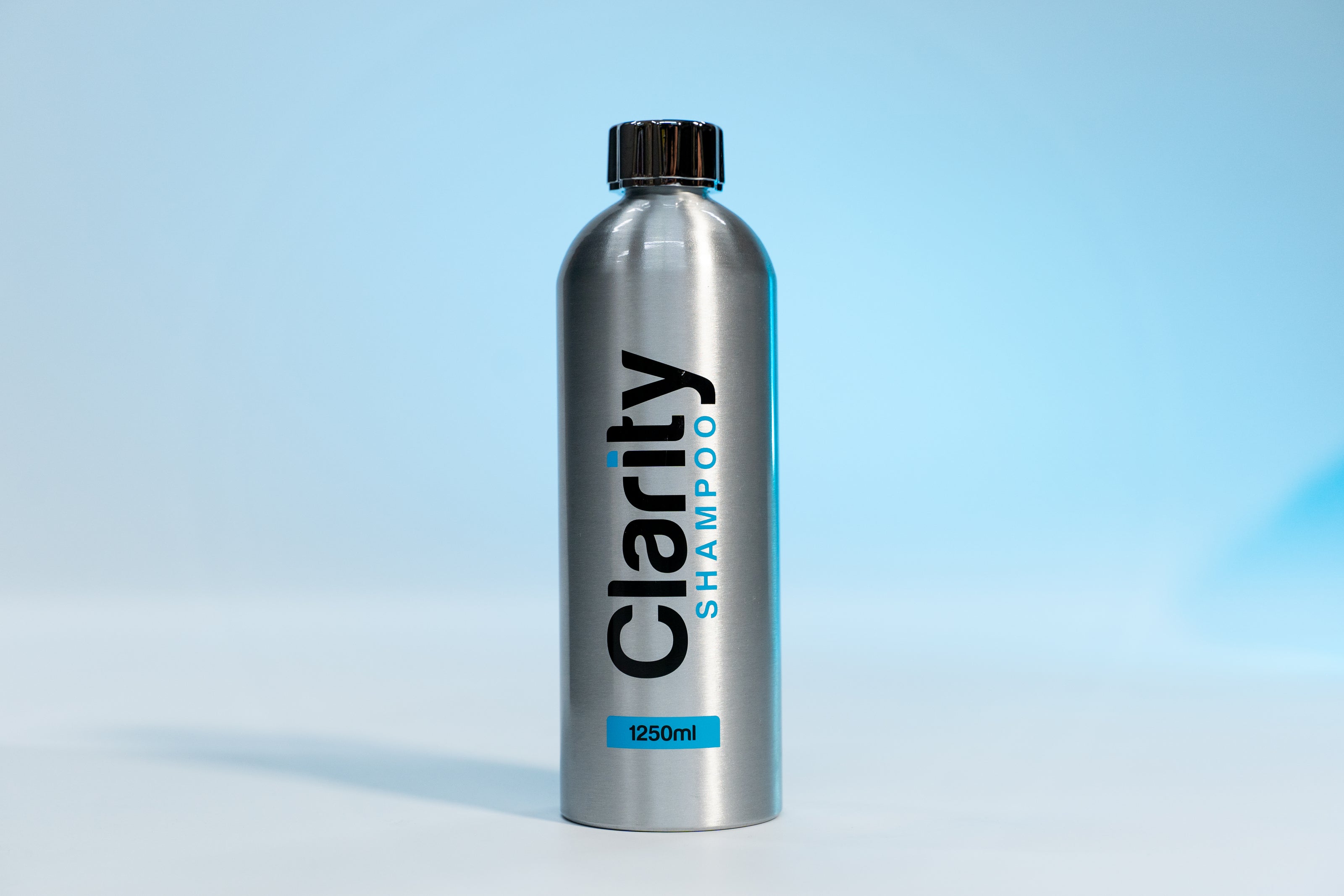 Silver shampoo bottle labeled 'Clarity Shampoo' on a light blue background