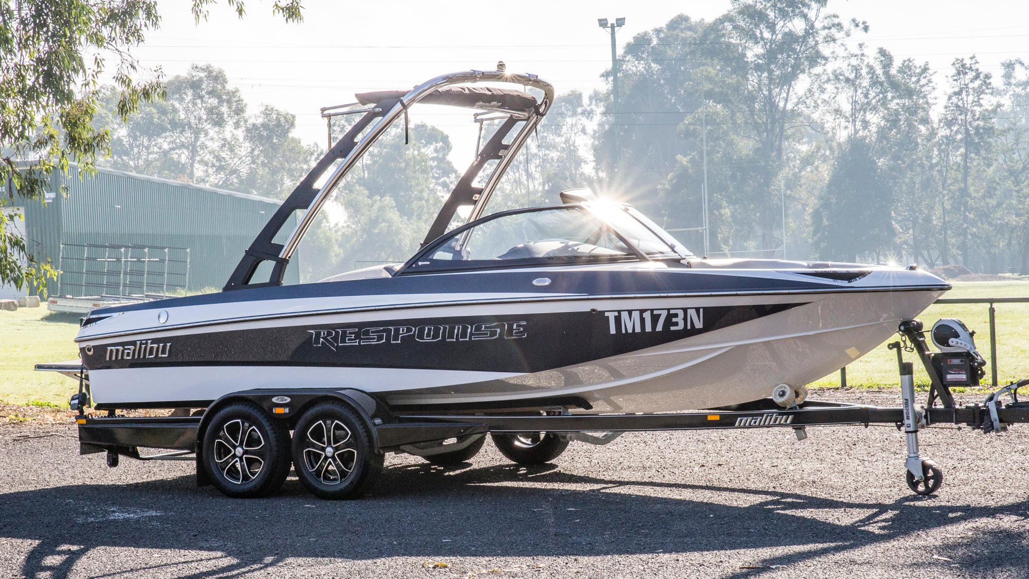 Malibu boat on a trailer with trees in the background